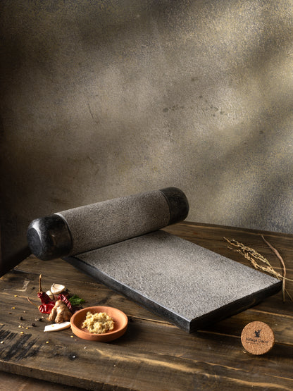 Traditional Handmade silbatta placed on table surrounded by fresh ingredients.